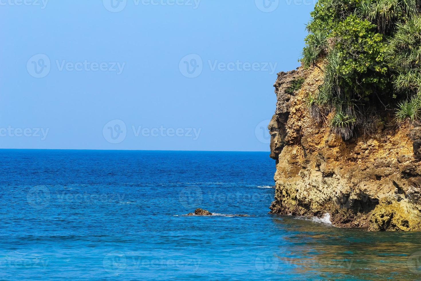 Rocky cliff at the beach. Bright  blue Sky and beautiful ocean as the background photo