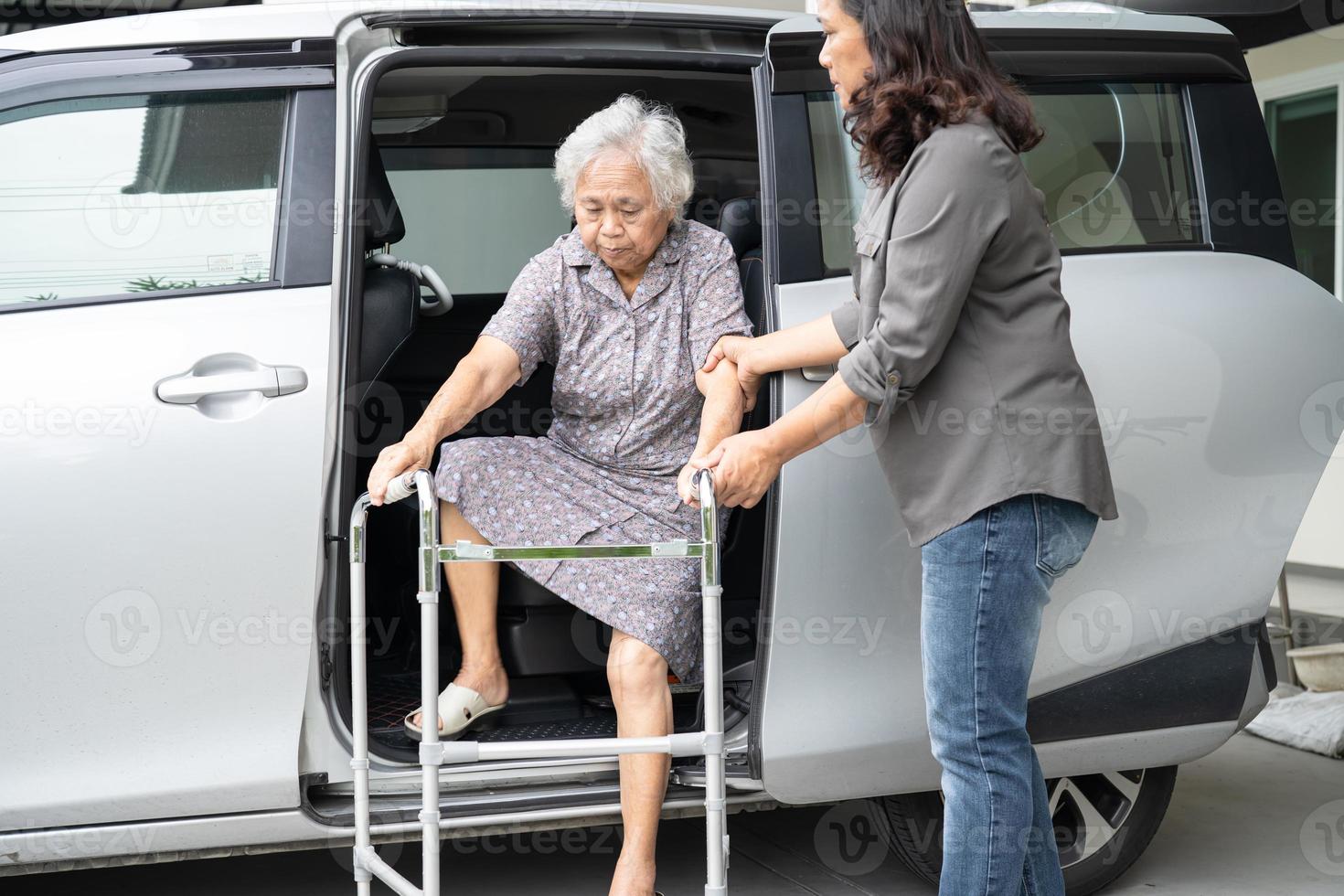 asiático mayor mujer paciente sentado en caminante preparar obtener a su auto, sano fuerte médico concepto. foto