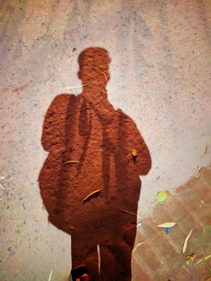 Shadow of a School Boy standing with Bag on City Street. Shadow of a men on street concrete background.Dark shadow on the street of the countryside. Shadow of a young man. photo