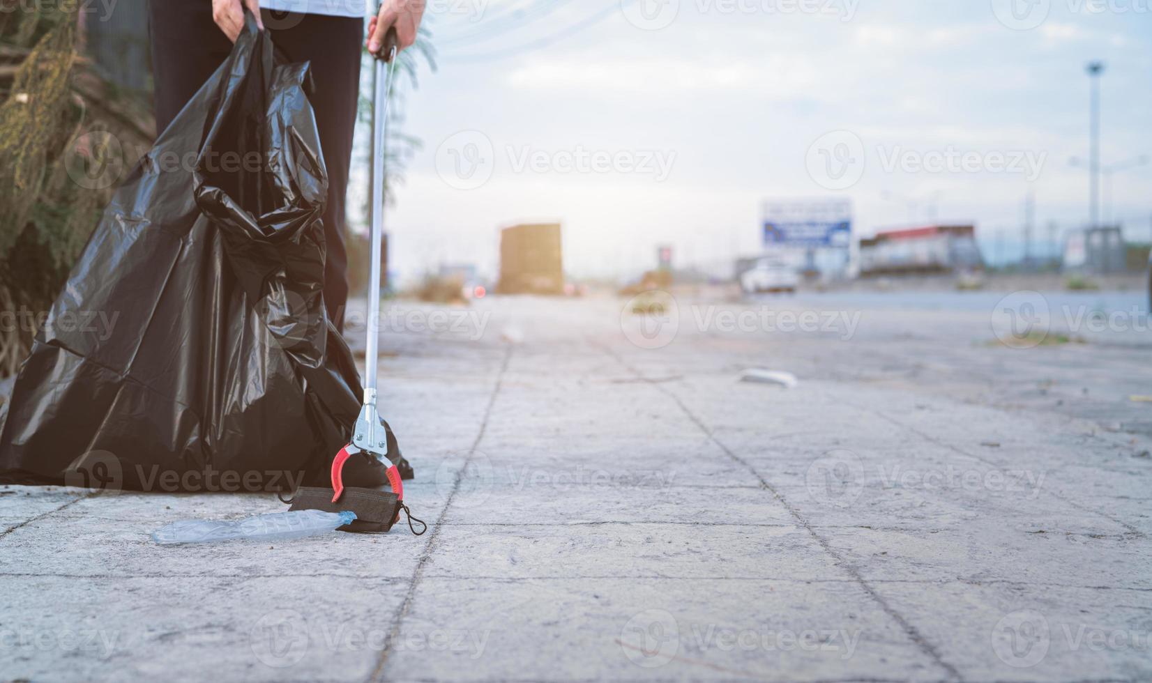 Volunteer collecting used medical face mask near plastic bottle into trash plastic bag for cleaning urban street. Clean up community garbage. World environment day, save the earth. Medical waste. photo