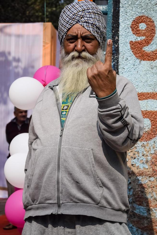 New Delhi, India - December 04 2022 - Unidentified people showing their ink-marked fingers after casting votes in front of polling booth of east Delhi area for MCD local body Elections 2022 photo