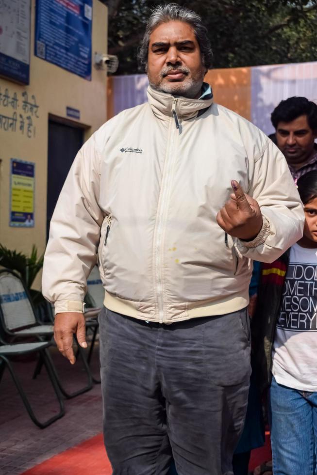 New Delhi, India - December 04 2022 - Unidentified people showing their ink-marked fingers after casting votes in front of polling booth of east Delhi area for MCD local body Elections 2022 photo