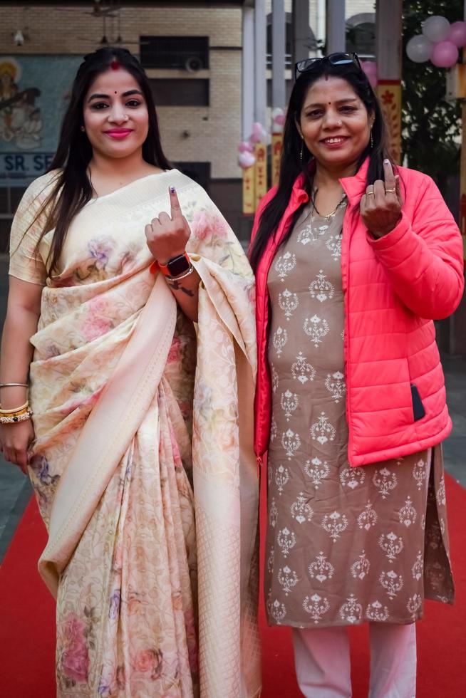 New Delhi, India - December 04 2022 - Unidentified people showing their ink-marked fingers after casting votes in front of polling booth of east Delhi area for MCD local body Elections 2022 photo