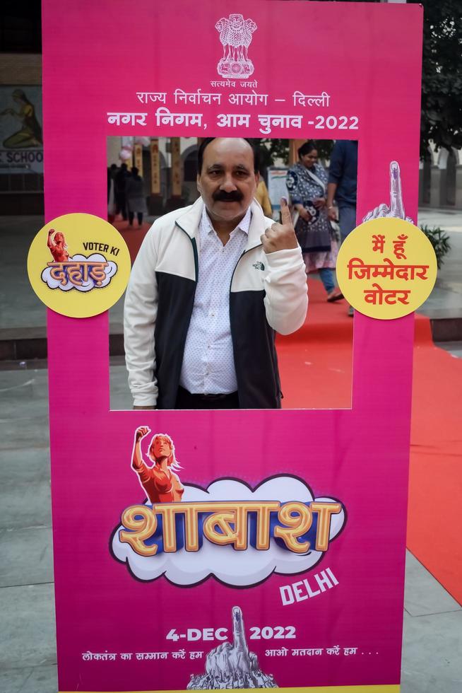 New Delhi, India - December 04 2022 - Unidentified people showing their ink-marked fingers after casting votes in front of polling booth of east Delhi area for MCD local body Elections 2022 photo