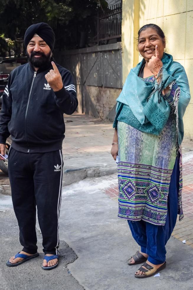 New Delhi, India - December 04 2022 - Unidentified people showing their ink-marked fingers after casting votes in front of polling booth of east Delhi area for MCD local body Elections 2022 photo