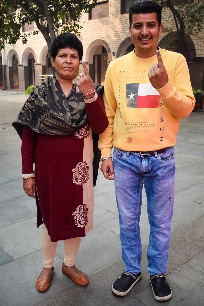 New Delhi, India - December 04 2022 - Unidentified people showing their ink-marked fingers after casting votes in front of polling booth of east Delhi area for MCD local body Elections 2022 photo