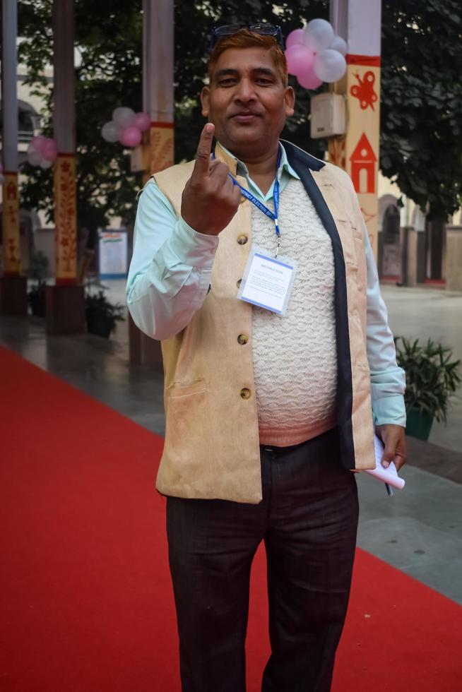 New Delhi, India - December 04 2022 - Unidentified people showing their ink-marked fingers after casting votes in front of polling booth of east Delhi area for MCD local body Elections 2022 photo