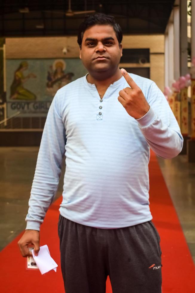 New Delhi, India - December 04 2022 - Unidentified people showing their ink-marked fingers after casting votes in front of polling booth of east Delhi area for MCD local body Elections 2022 photo