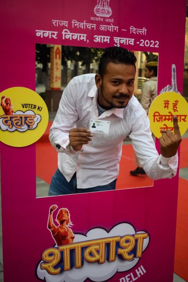 New Delhi, India - December 04 2022 - Unidentified people showing their ink-marked fingers after casting votes in front of polling booth of east Delhi area for MCD local body Elections 2022 photo