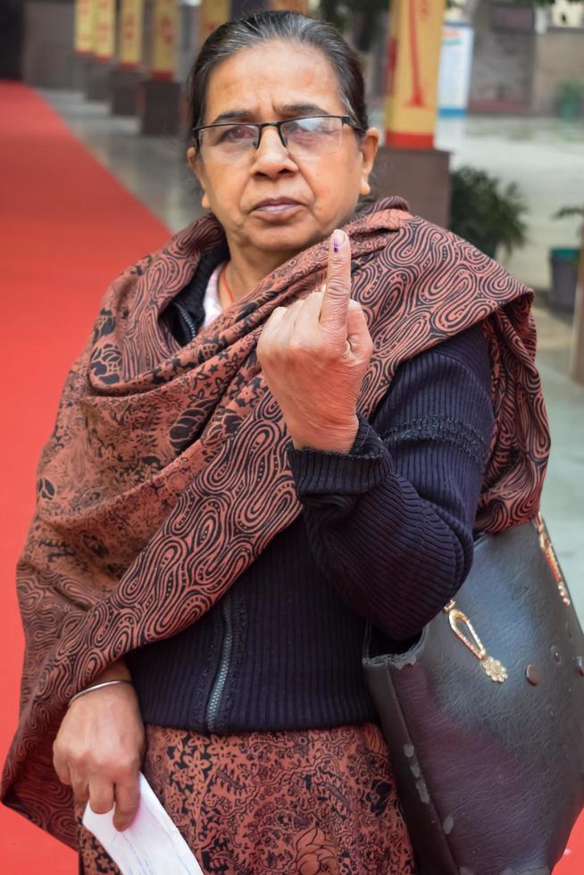 New Delhi, India - December 04 2022 - Unidentified people showing their ink-marked fingers after casting votes in front of polling booth of east Delhi area for MCD local body Elections 2022 photo