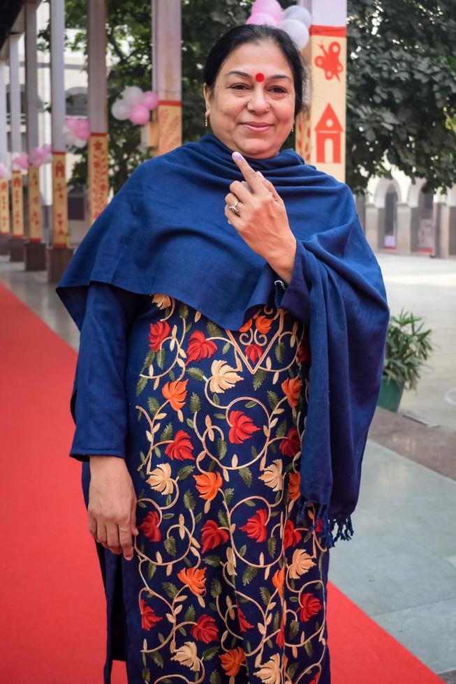 New Delhi, India - December 04 2022 - Unidentified people showing their ink-marked fingers after casting votes in front of polling booth of east Delhi area for MCD local body Elections 2022 photo