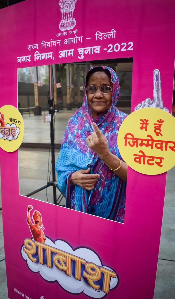 New Delhi, India - December 04 2022 - Unidentified people showing their ink-marked fingers after casting votes in front of polling booth of east Delhi area for MCD local body Elections 2022 photo