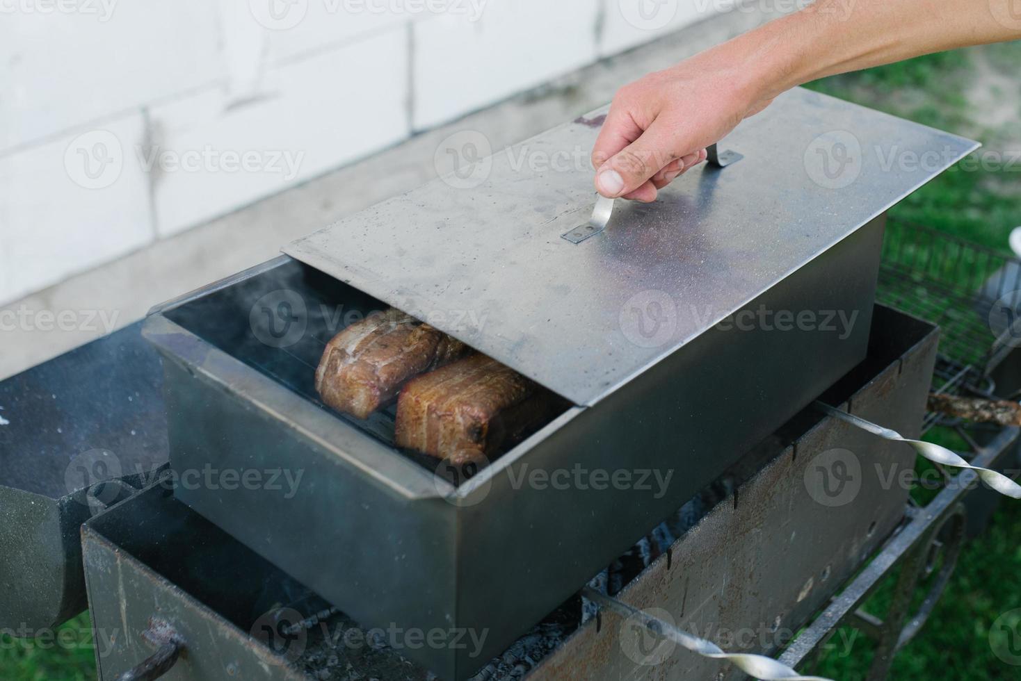 A man's hand opens a smokebox with lard in nature photo