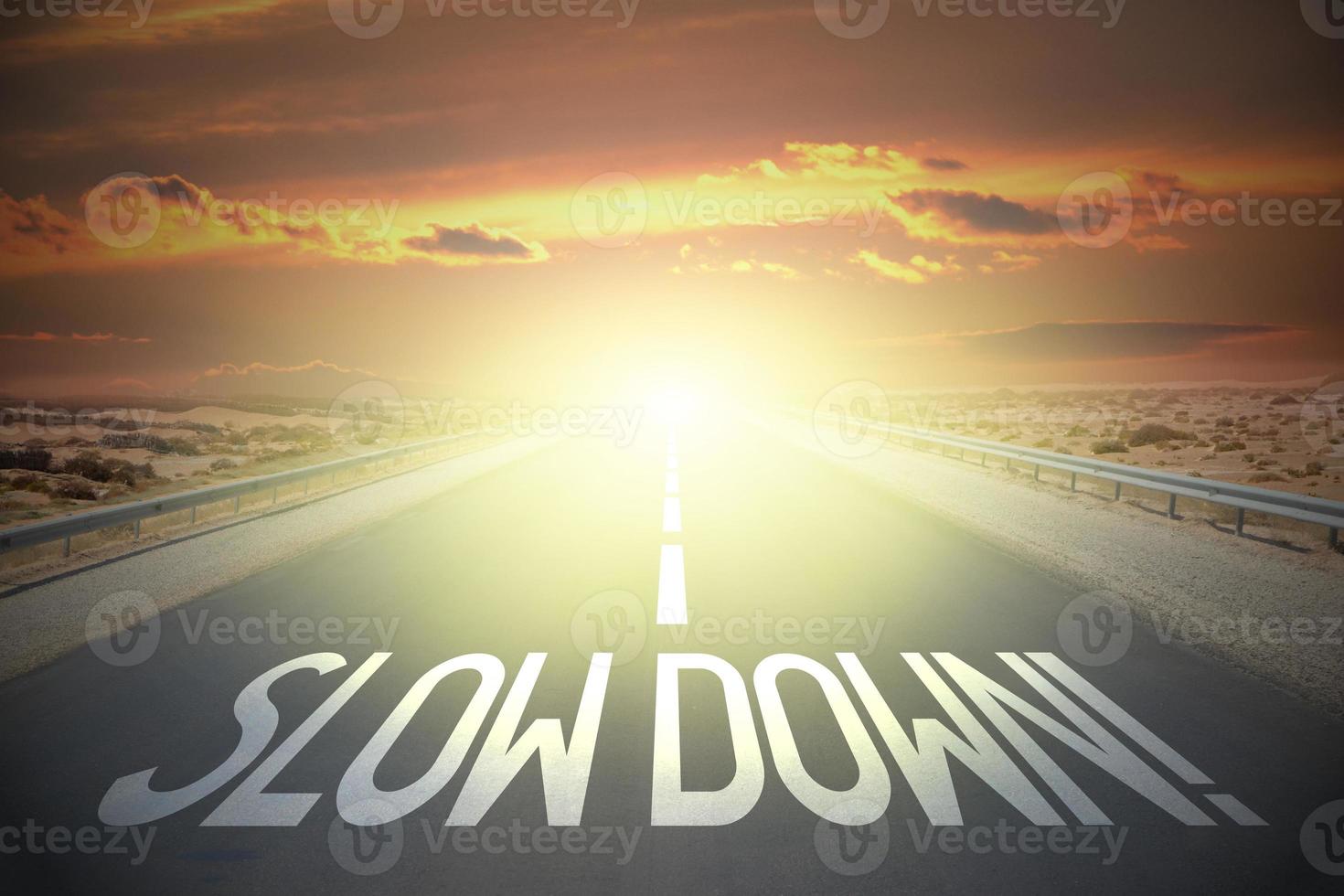 Slow down word on a road and sunset sky photo