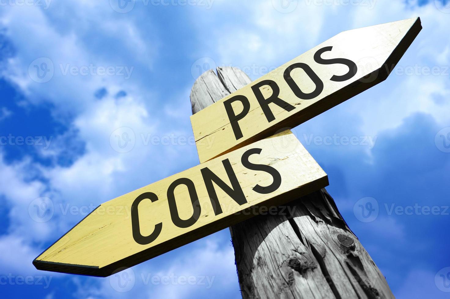 Pros, Cons - Wooden Signpost with Two Arrows and Sky in Background photo