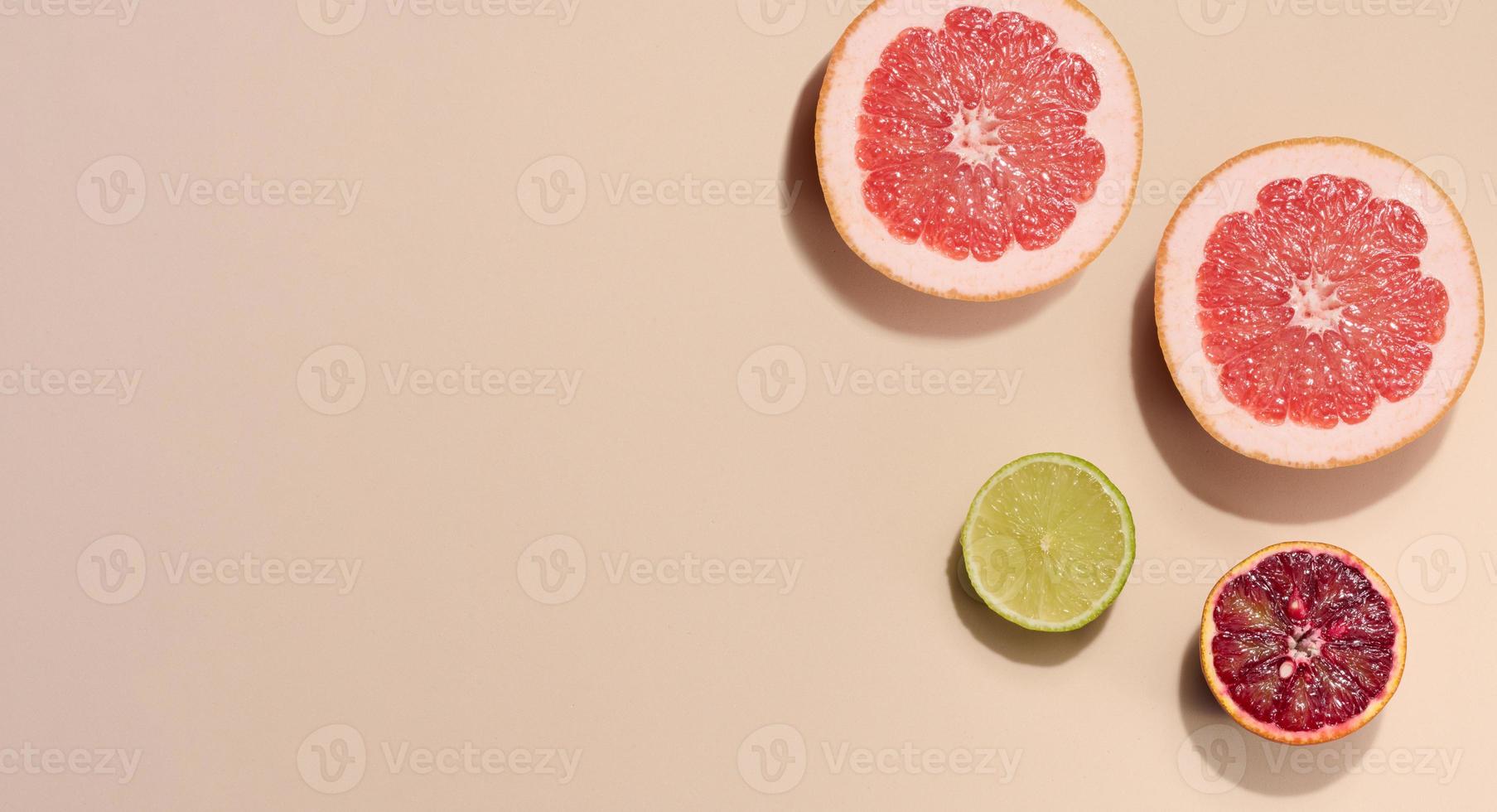 Sliced pieces of orange, lime and grapefruit on a beige background, top view photo