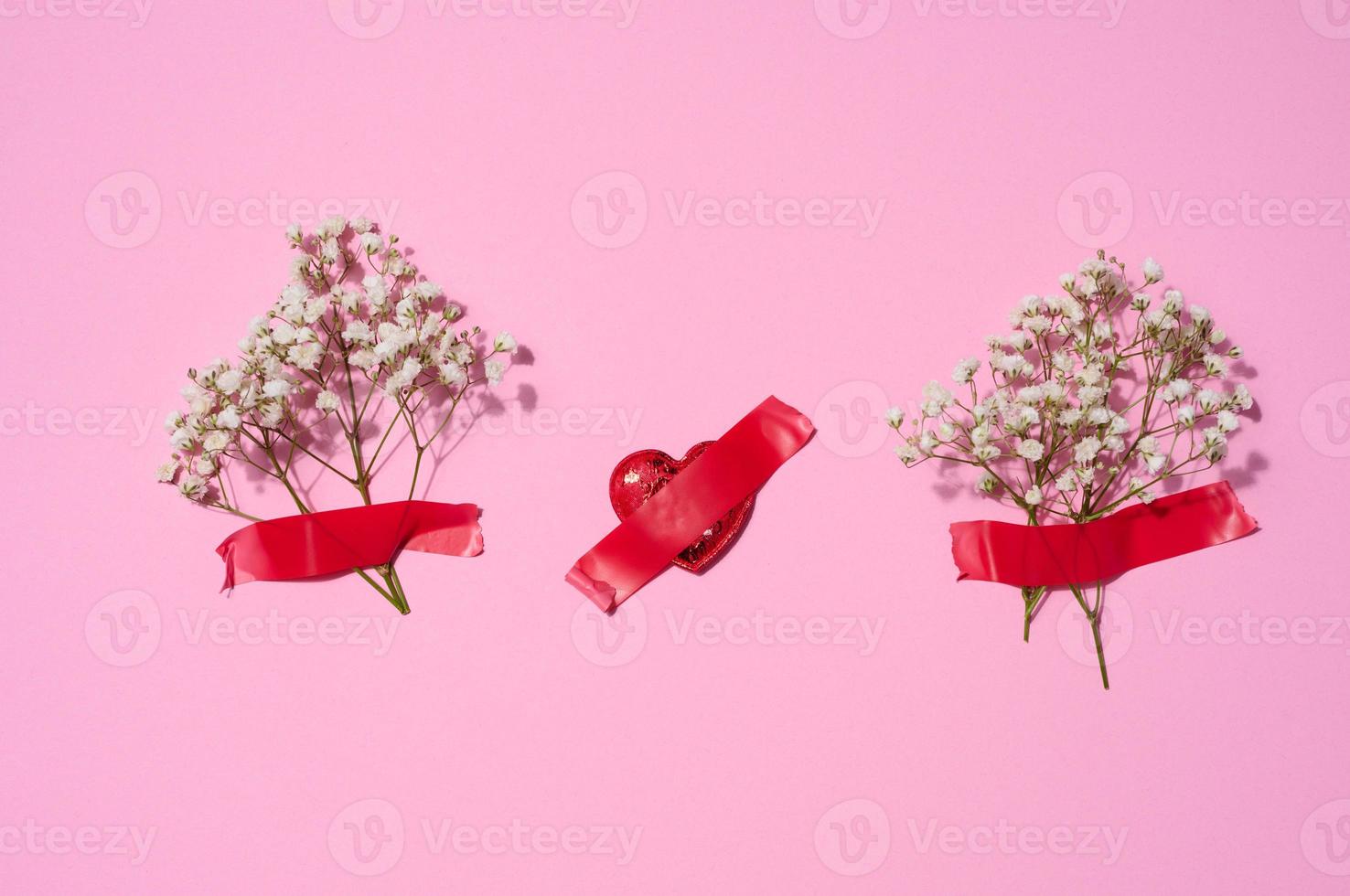 Bouquet of white gypsophila  and red textile hearts on a pink background, top view photo
