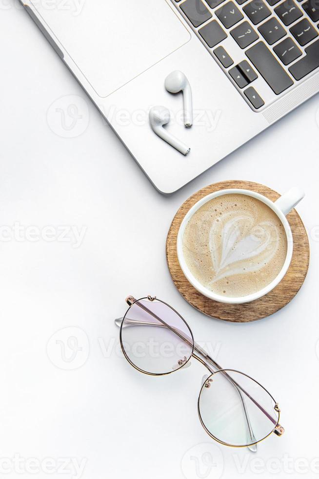 Modern white office desk table with laptop, notebook and other supplies. photo