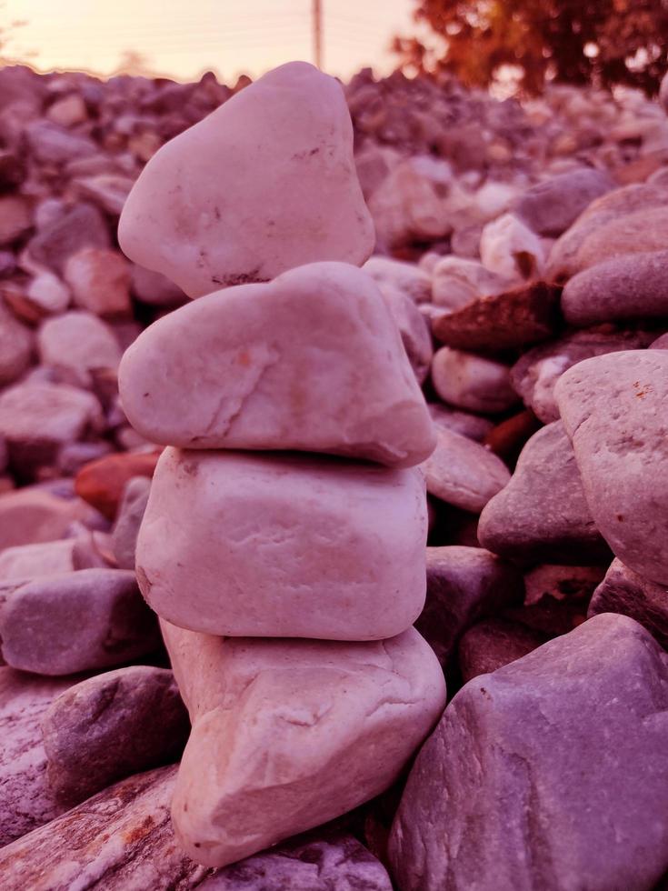 Stack of triangular stones.Group of white and colorful Stones.Pebble tower on the stones seaside.Stones pyramid on pebble beach symbolizing stability,zen,Rock,harmony,balance.Shallow depth of field. photo