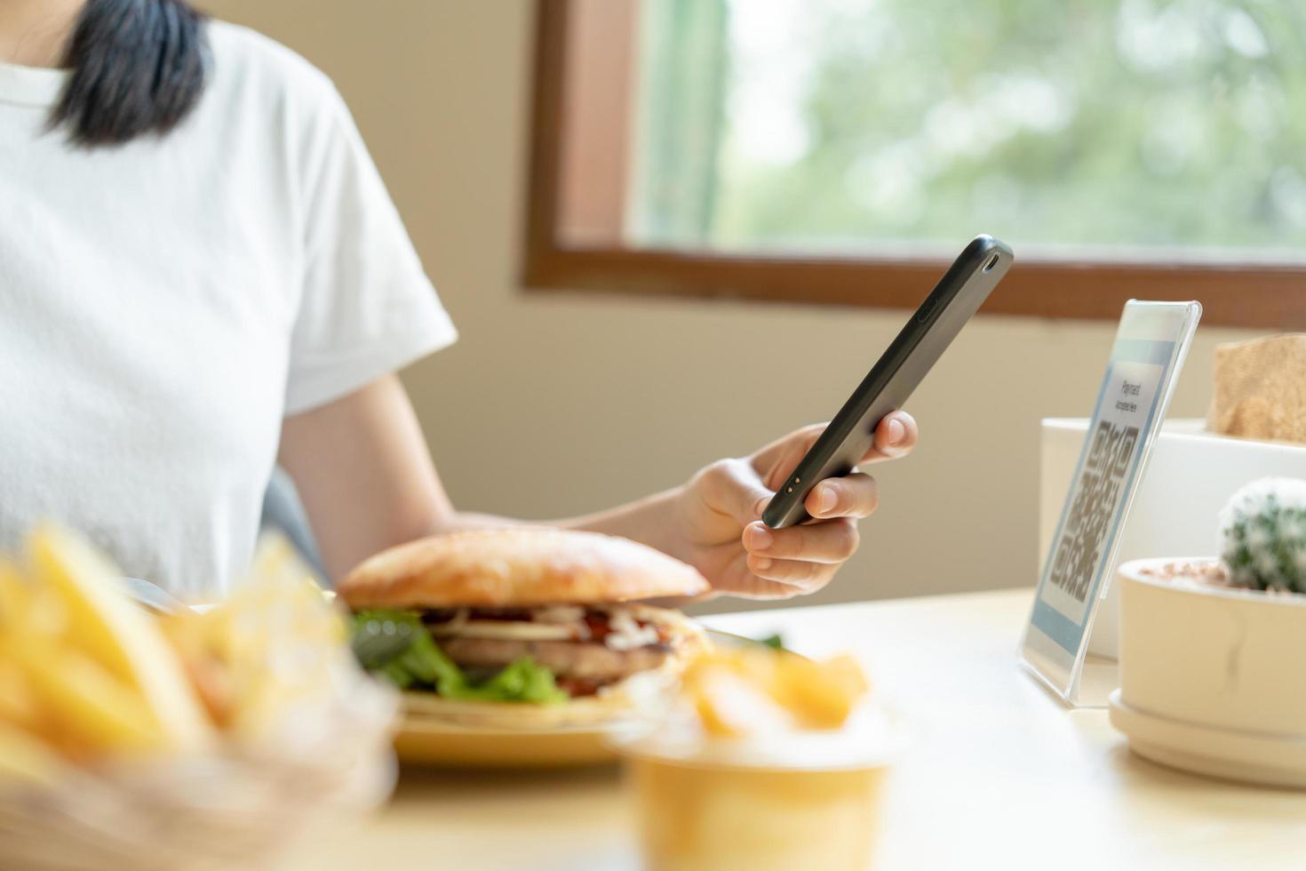 Woman use smartphone to scan QR code to pay in cafe restaurant with a digital payment without cash. Choose menu and order accumulate discount. E wallet, technology, pay online, credit card, bank app. photo