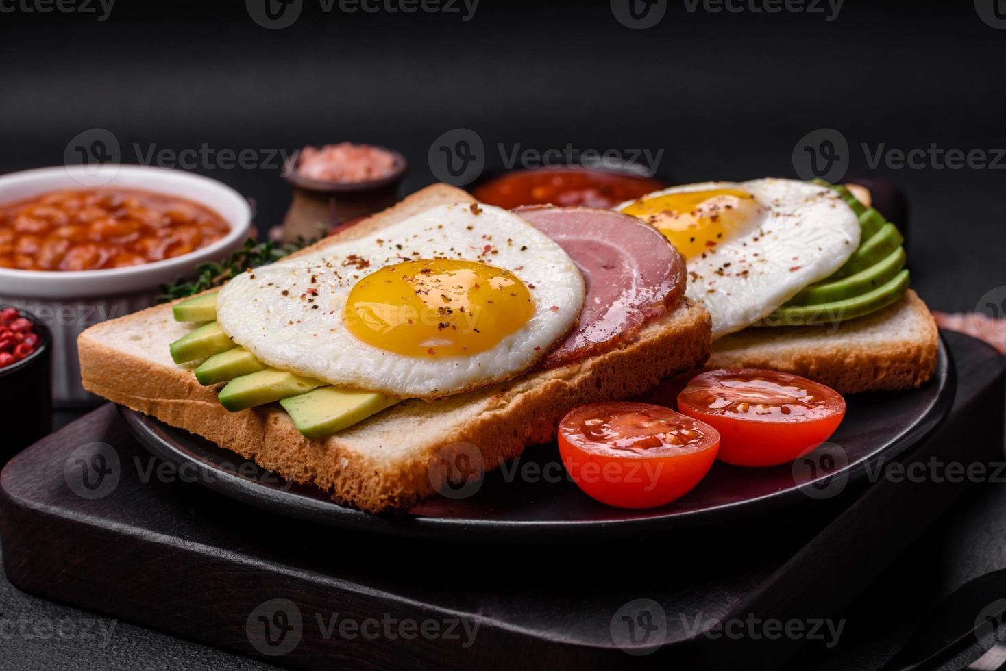 Delicious nutritious English breakfast with fried eggs, tomatoes and avocado photo