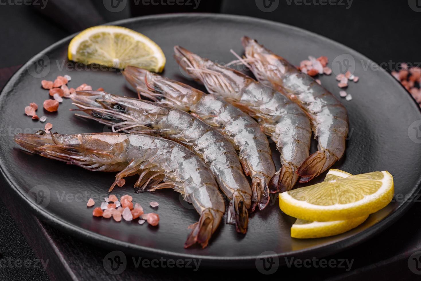 Tiger prawn or langoustine raw with spices and salt on a wooden cutting board photo