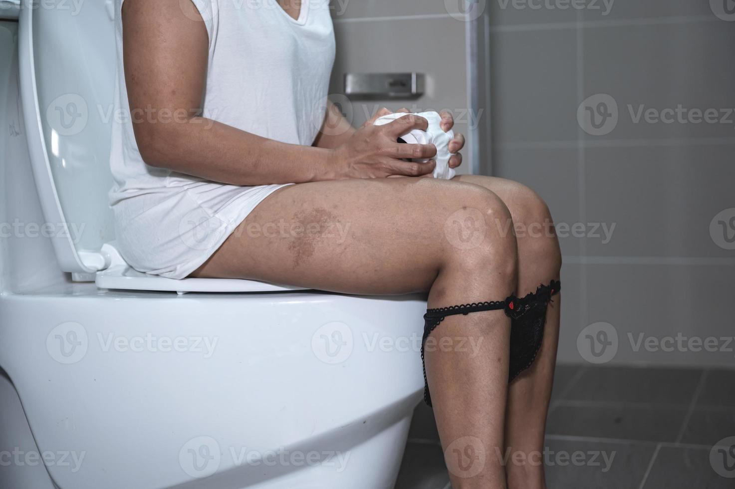 Have problems with excretion concept,An Asian woman sits on the toilet bowl,Constipation and a long time in the toilet. photo