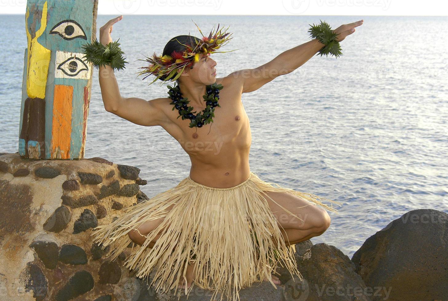 Male hula dancer poses in front of the ocean as the sun sets. photo