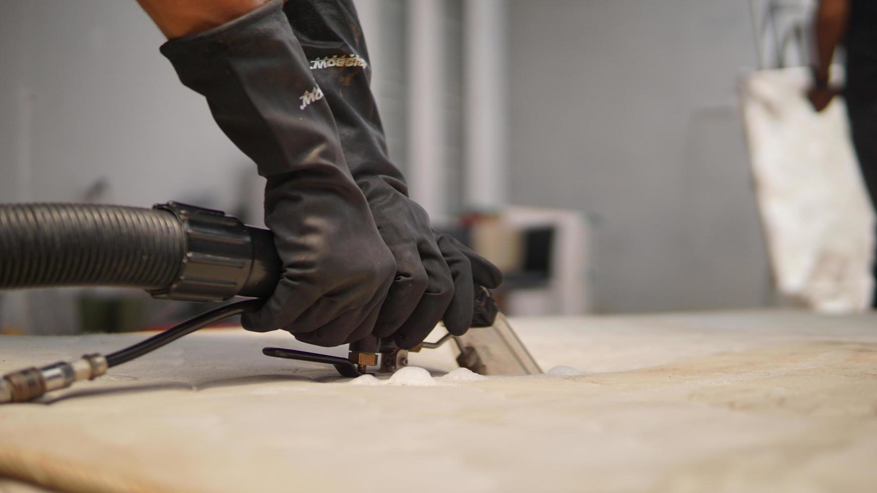 Close up of a man's hands in black gloves working cleaning sofa photo