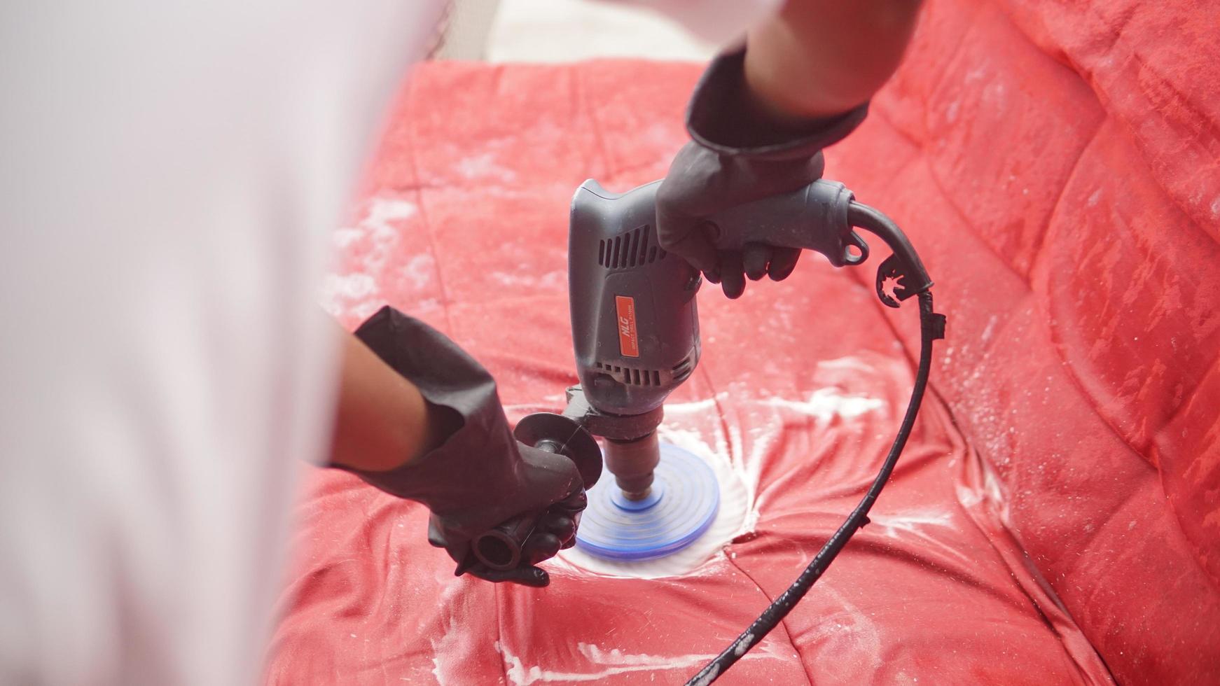 Worker polishing a red sofa with an electric grinder. photo