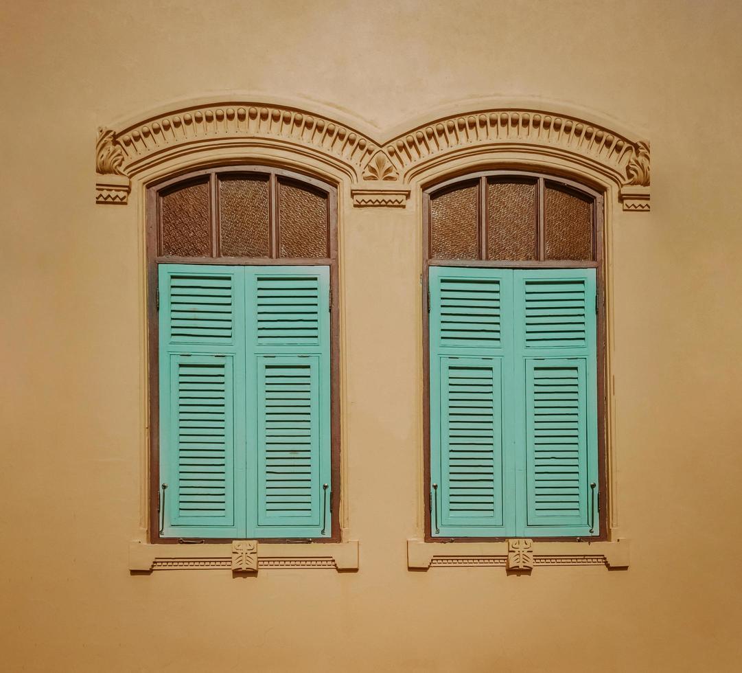 Vintage window with blue shutters on yellow wall background. Retro style. photo