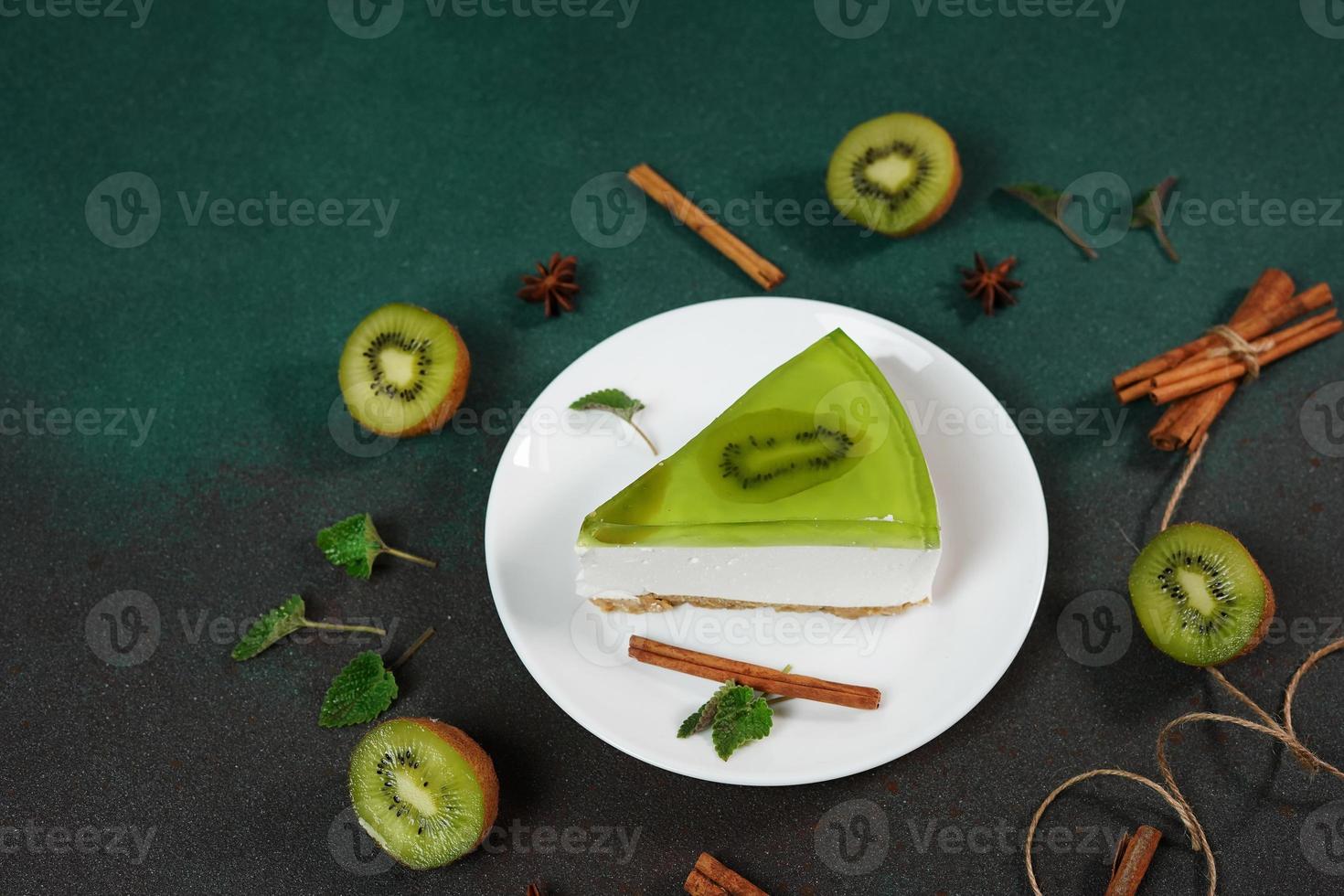 Cheesecake with Kiwi, cinnamon stick and leaves mint on a green background. Copy cpase for text photo