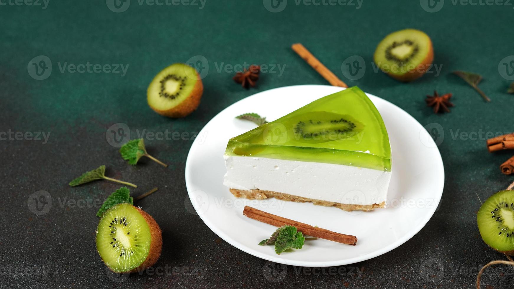 Cheesecake with Kiwi, cinnamon stick and leaves mint on a green background. Copy cpase for text photo