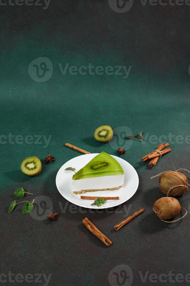 Cheesecake with Kiwi, cinnamon stick and leaves mint on a green background. Copy cpase for text photo