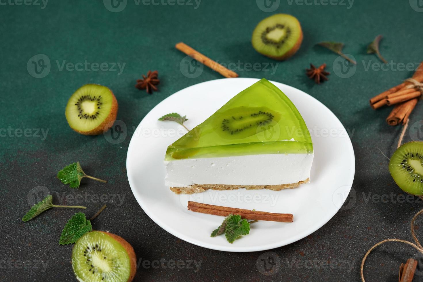 Cheesecake with Kiwi, cinnamon stick and leaves mint on a green background. Copy cpase for text photo