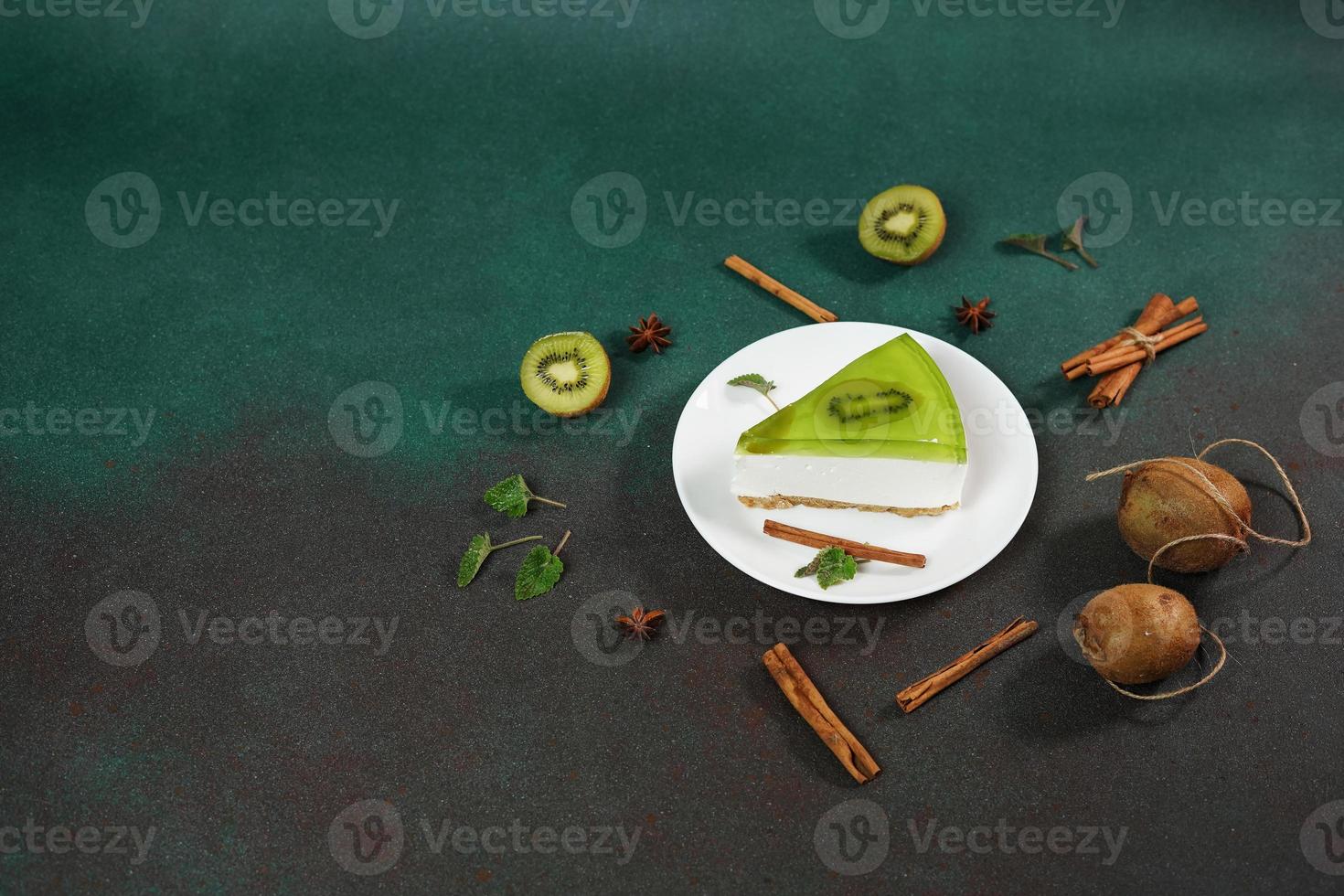 Cheesecake with Kiwi, cinnamon stick and leaves mint on a green background. Copy cpase for text photo