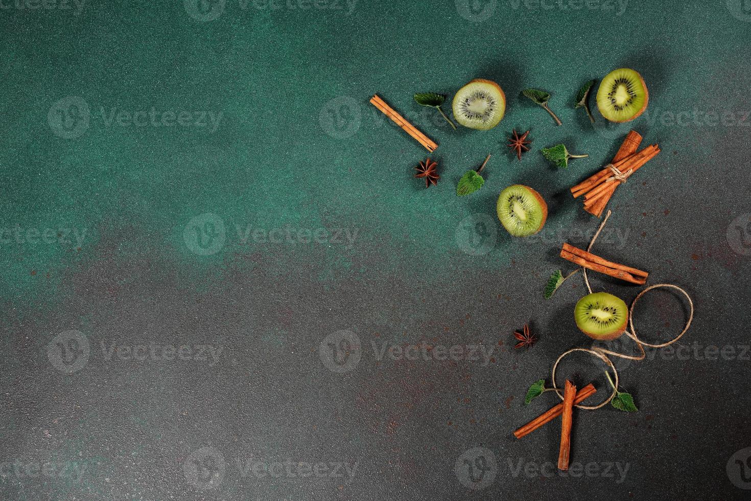 Slices of fresh, juicy Kiwi on a Green background. Decorated with cinnamon sticks, badyan, mint leaves. Fruity decorated background. Top view photo