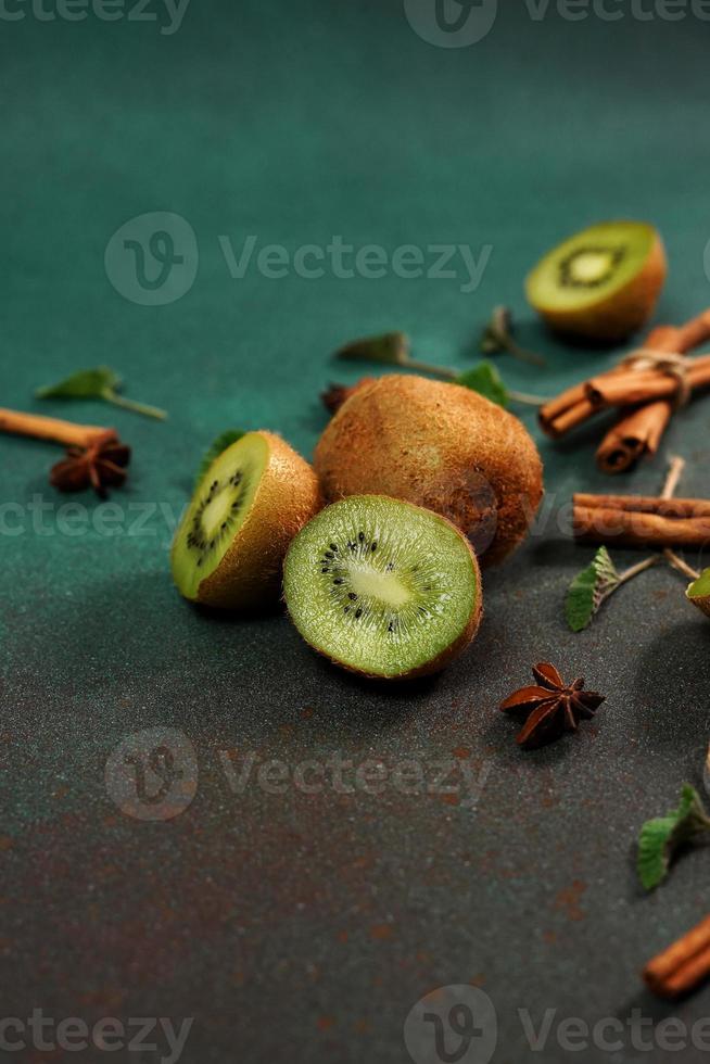 Slices of fresh, juicy Kiwi on a Green background. Decorated with cinnamon sticks, badyan, mint leaves. Fruity decorated background photo