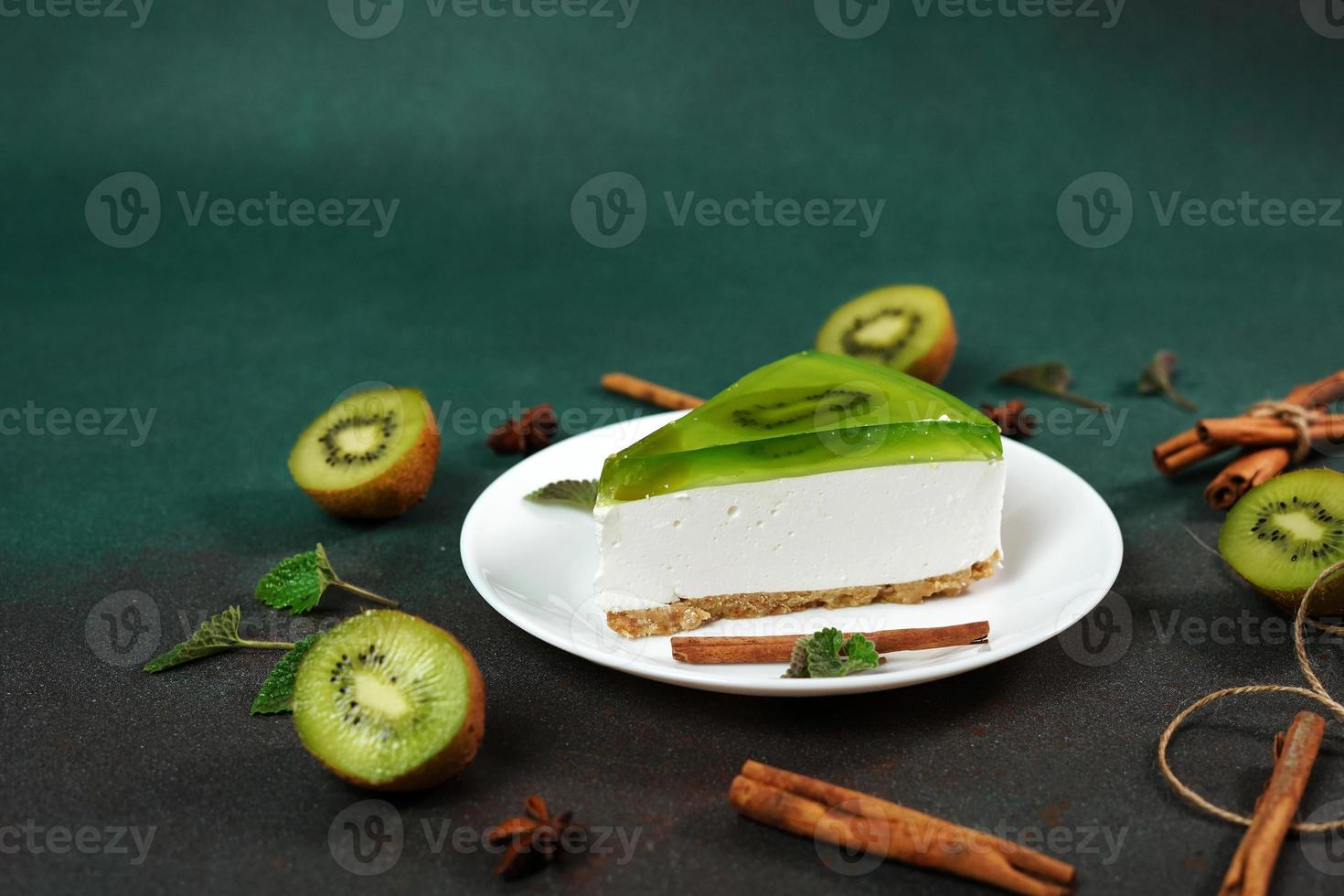 Cheesecake with Kiwi, cinnamon stick and leaves mint on a green background. Copy cpase for text photo