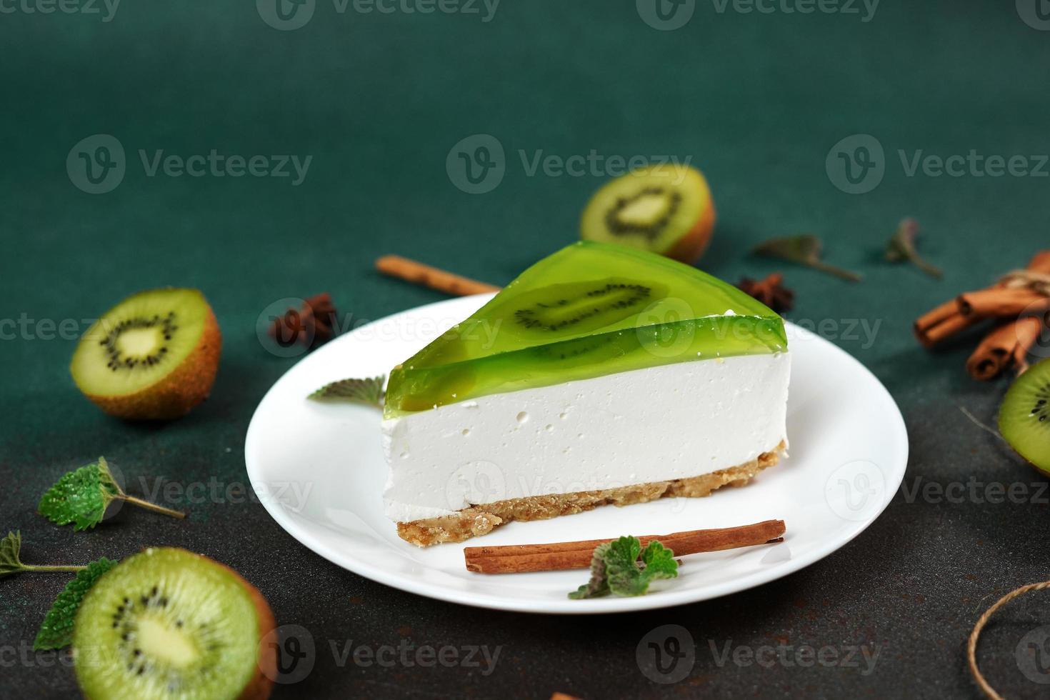 Cheesecake with Kiwi, cinnamon stick and leaves mint on a green background. Copy cpase for text photo