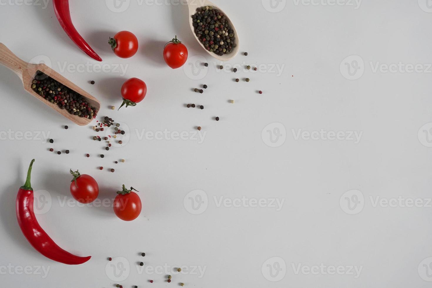 Cherry Tomatoes, red hot chili Pepper, fragrant black pepper peas on a White Background. Background with Spices. Flat lay, Copy space photo