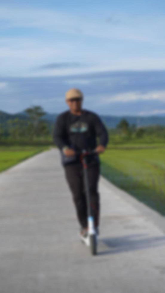 blurred background of a man is riding a scooter on the road with a natural mountain view photo