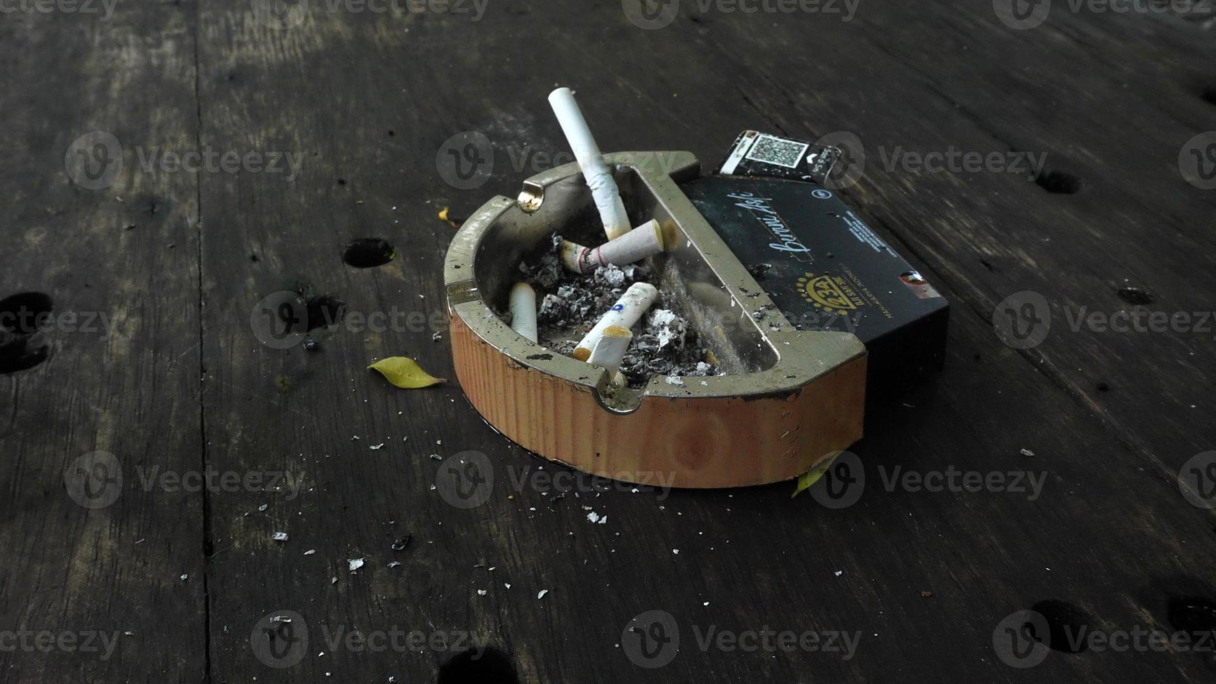 ashtray and cigarette butts on wooden table in outdoor bandung seafood restaurant photo