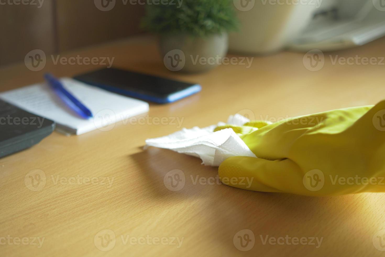 hand in rubber gloves cleaning table with cloth photo