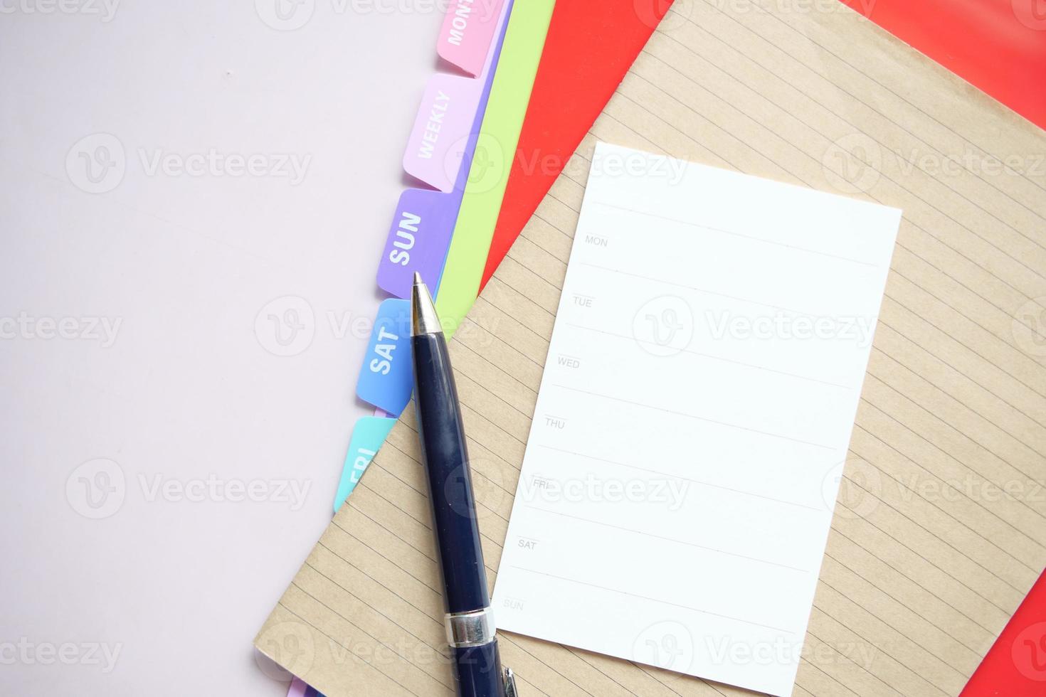 weekly planner and notepad on table photo