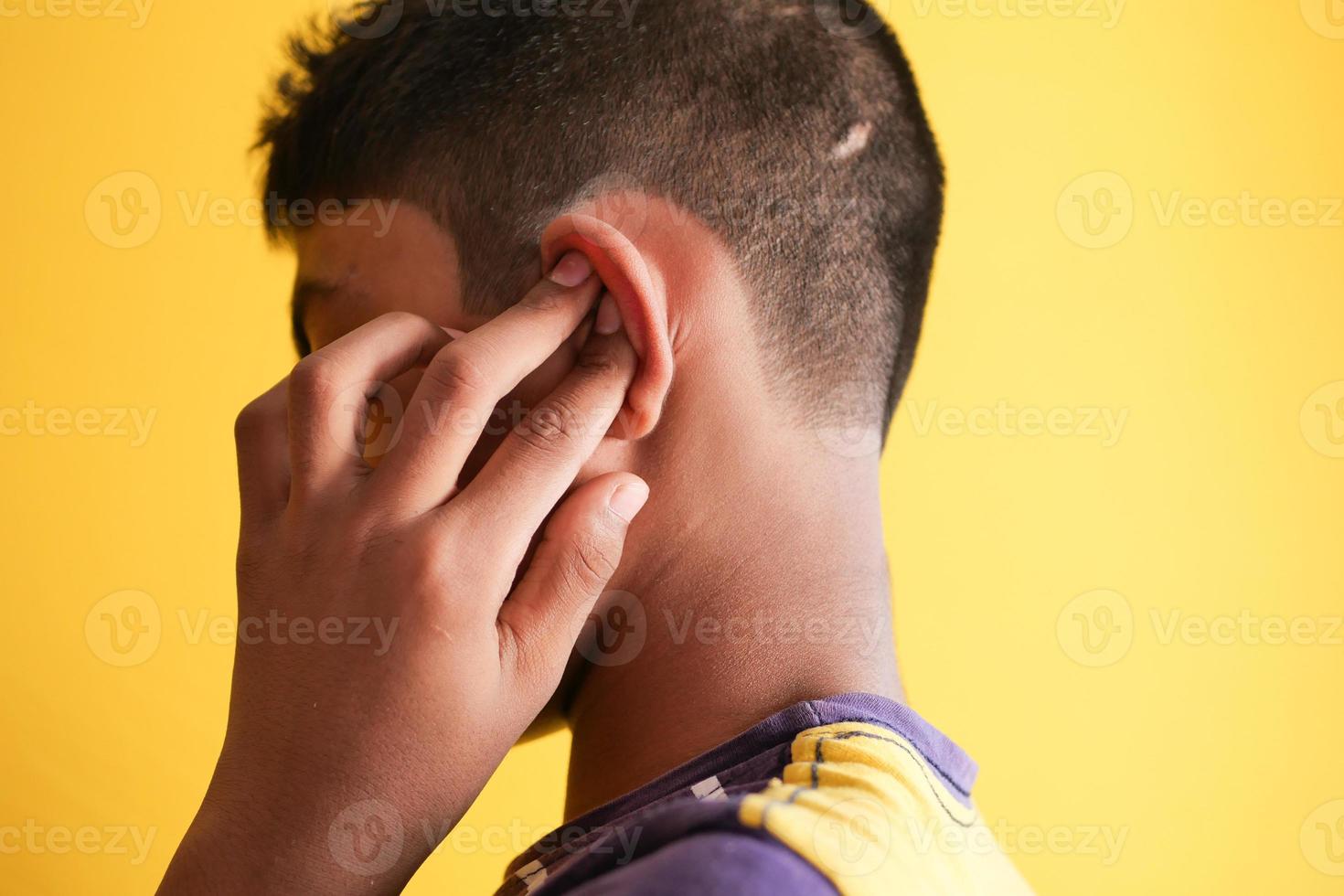 teenage boy having ear pain touching his painful ear , photo