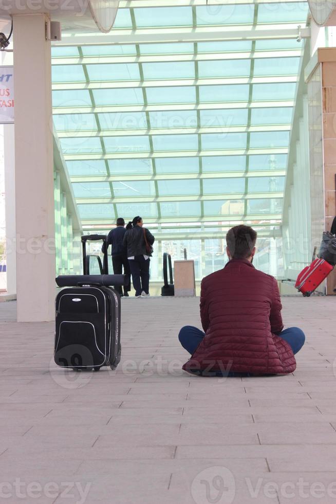 Man sitting with his back at the train station with his suitcases photo