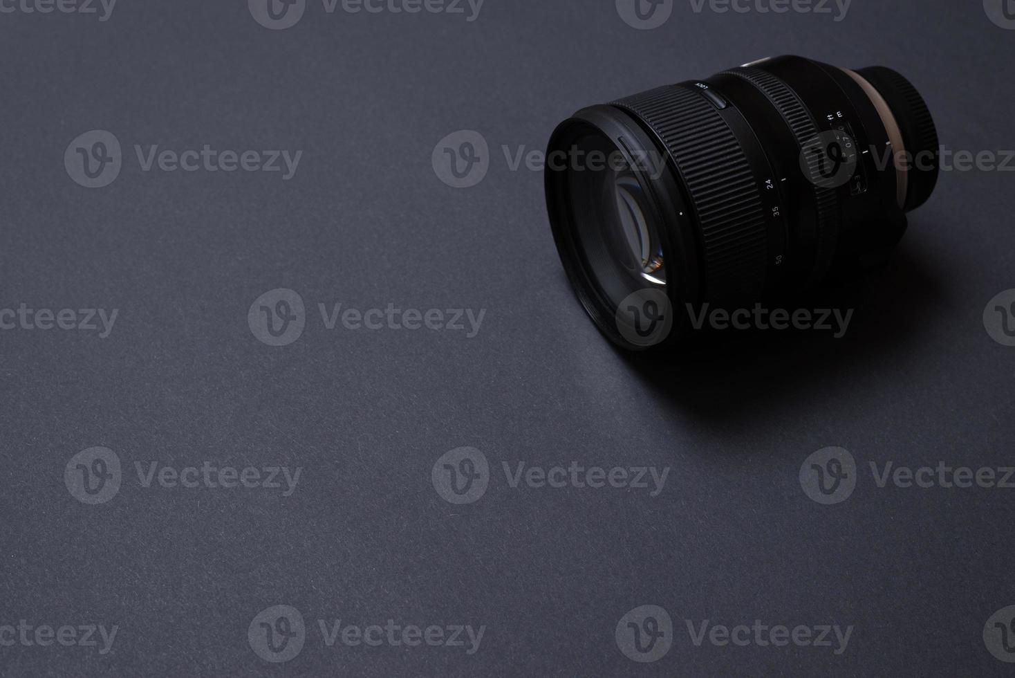 Modern camera lens on black office desk with copy space photo