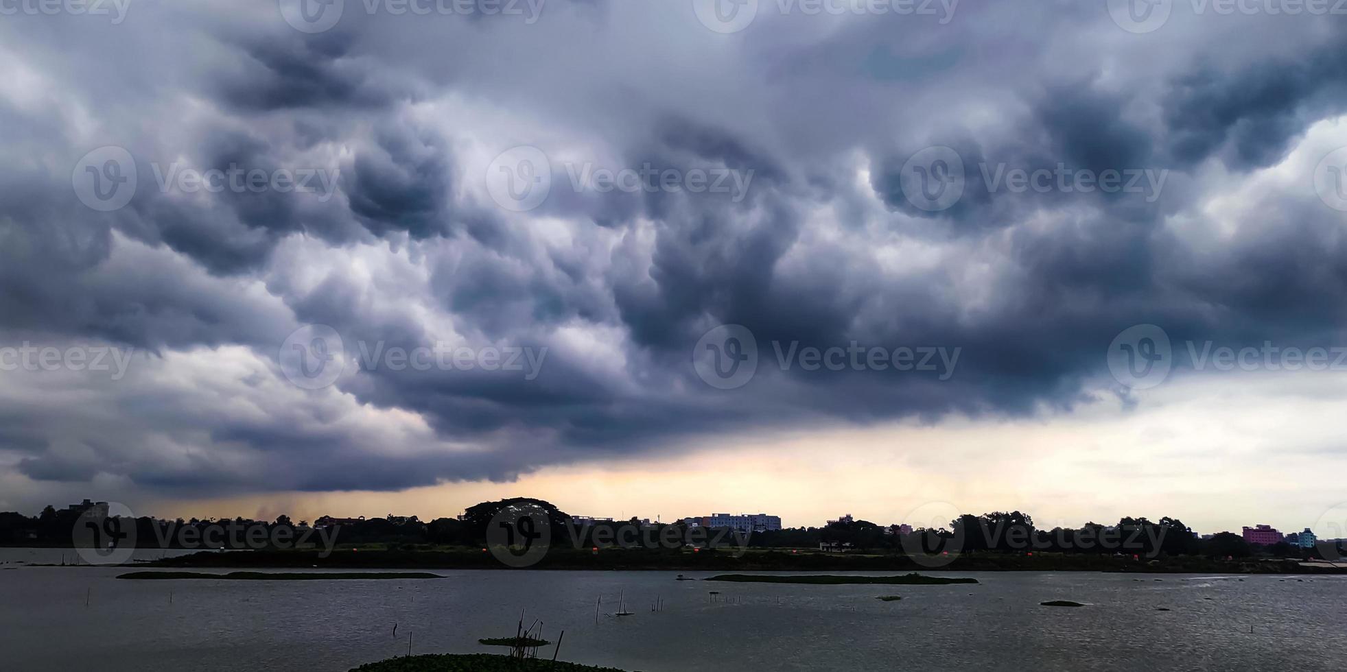 A cloudy sky over a lake, white sky with black cloud photo