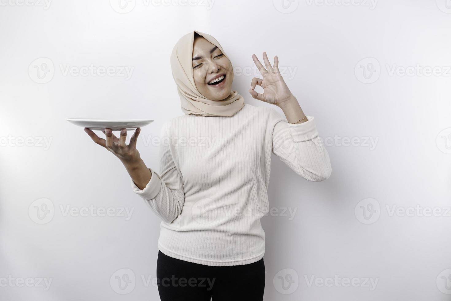 un sonriente asiático musulmán mujer es rápido y hambriento y participación y señalando a un plato foto